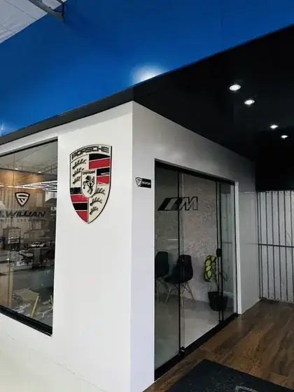 Sala de espera da oficina, com o brasão da Porsche na parede