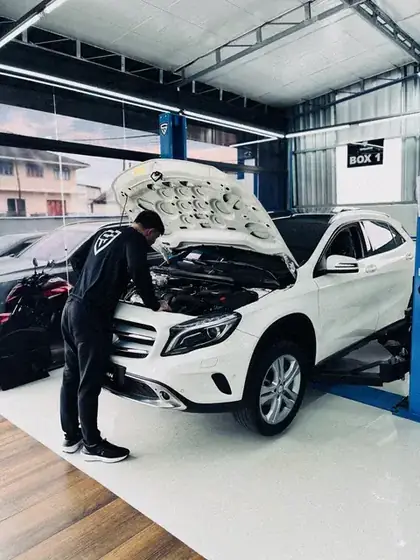 Técnico da oficina trabalhando no motor de um Mercedes GLA branco