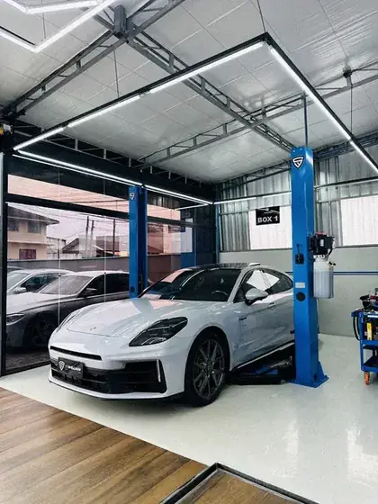 Porsche Panamera branco no box 1, sob o teto de luz hexagonal
