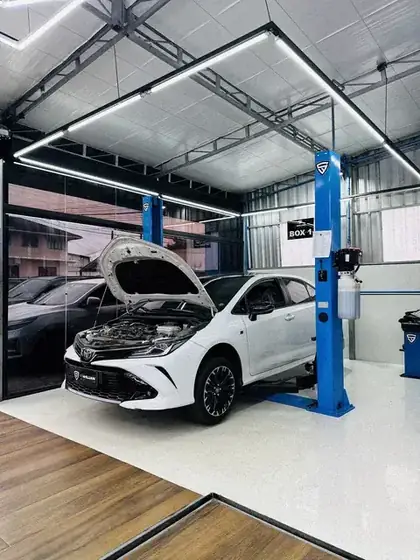 Toyota Corolla de capô aberto sob o teto de luz hexagonal